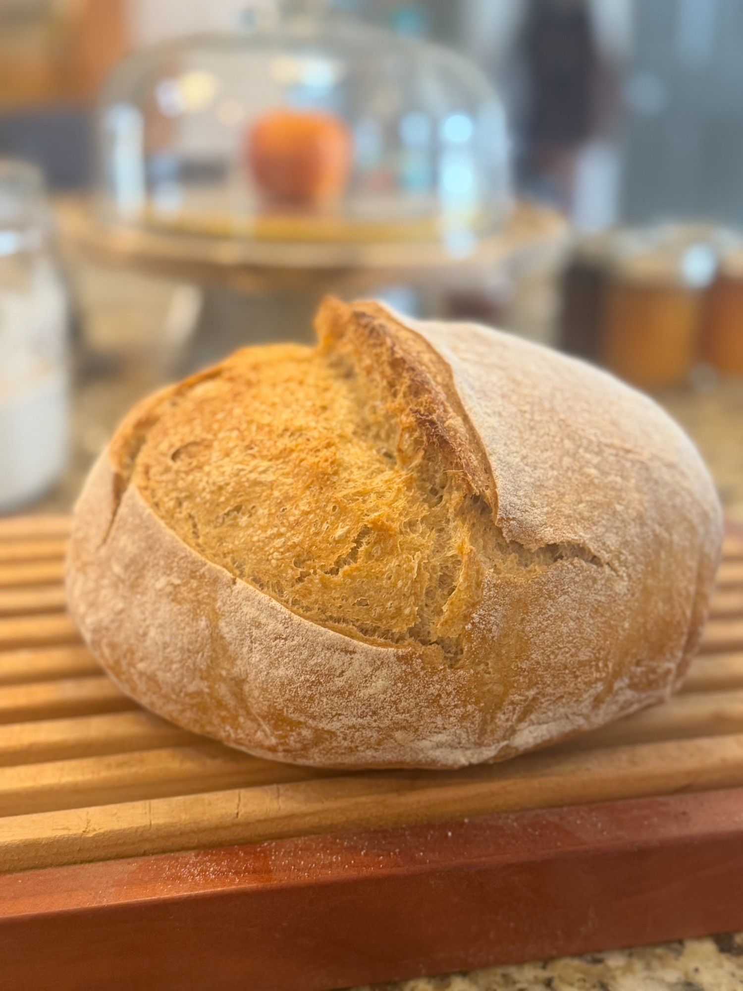 A perfect sourdough boule with a golden crackling crust on a wooden board